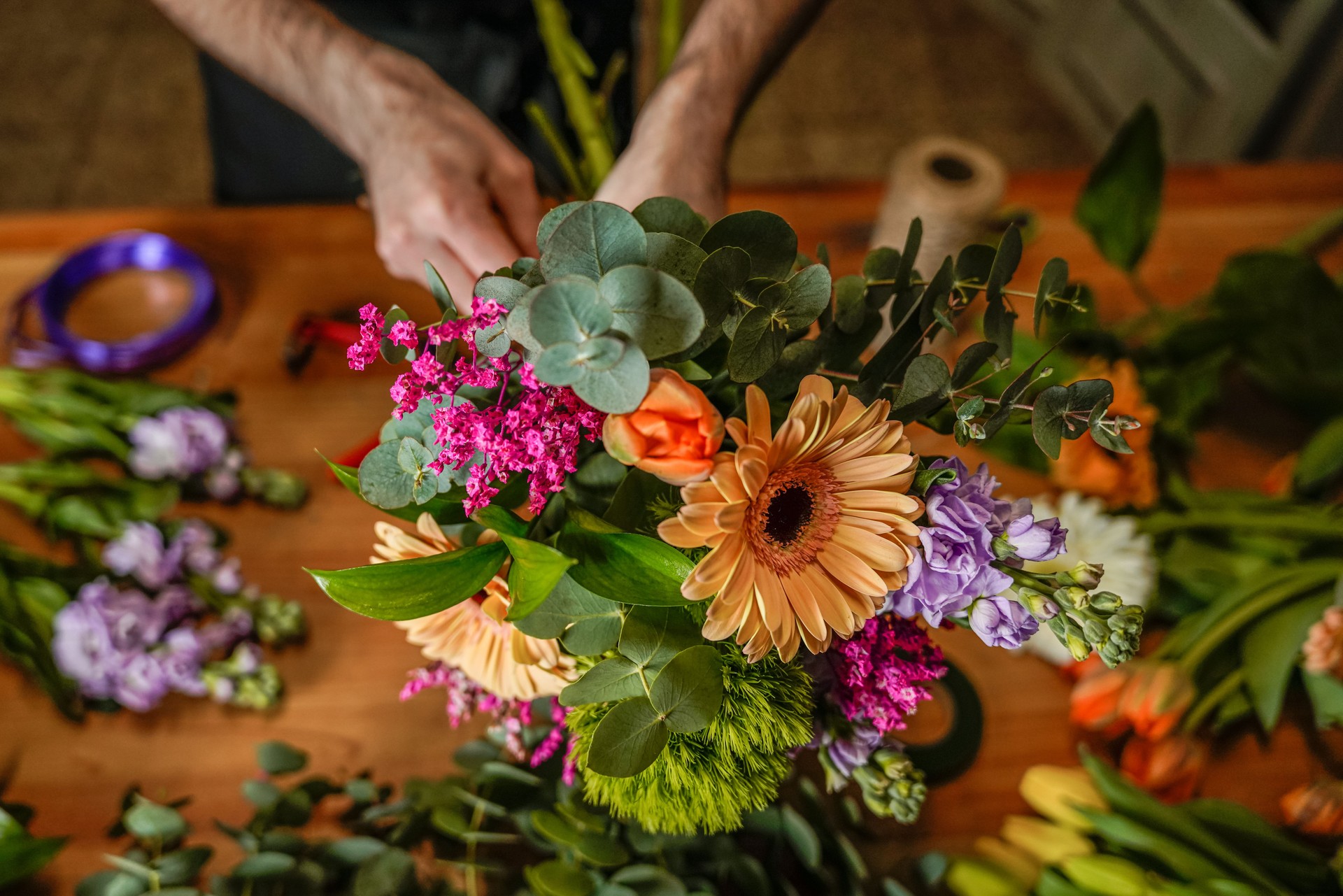 Florist arranging a colorful bouquet with gerbera, eucalyptus and other flowers